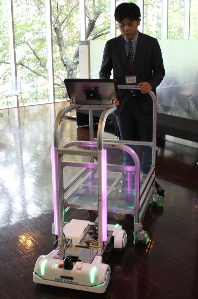 THKの自律搬送ロボットと患者の荷物を入れるカート